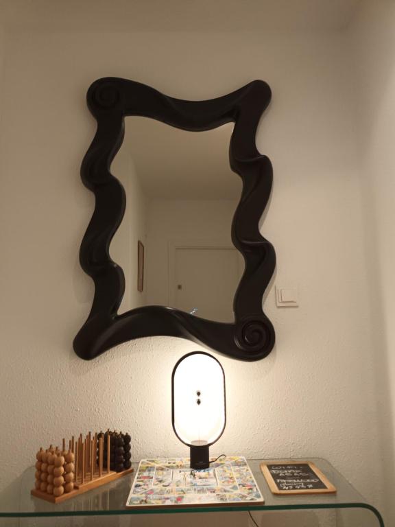 een tafel met een lamp en een spiegel aan een muur bij La H escondida Valencia in Valencia