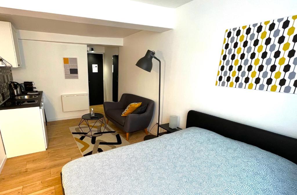 a bedroom with a bed and a chair and a kitchen at Appart' Châtelet Hypercentre NETFLIX inclus in Orléans
