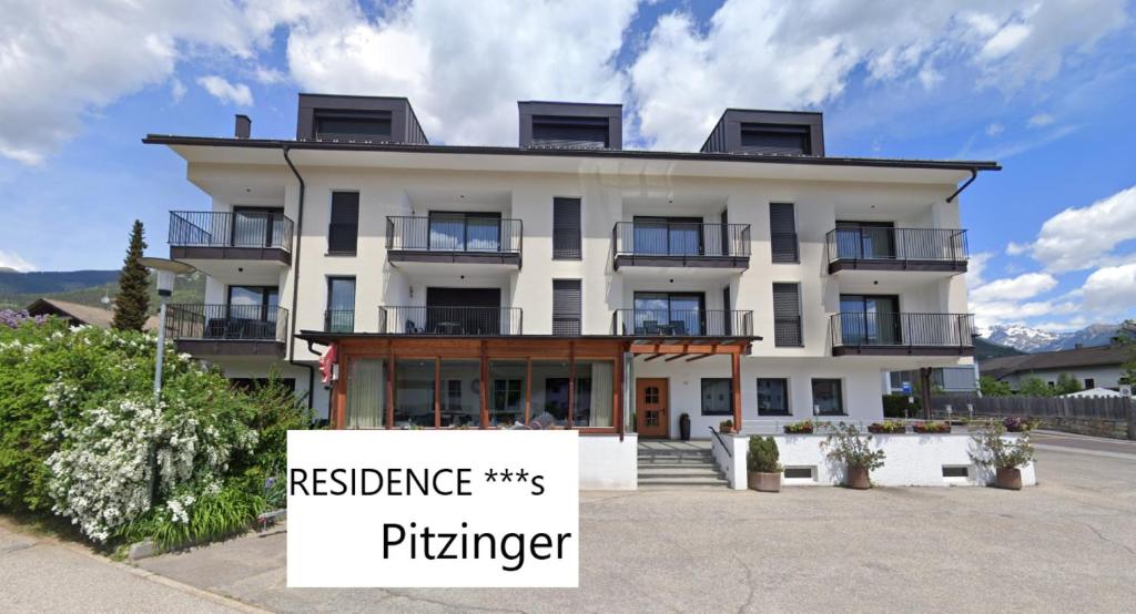 - un grand bâtiment blanc avec un panneau devant dans l'établissement Residence Pitzinger, à Falzes