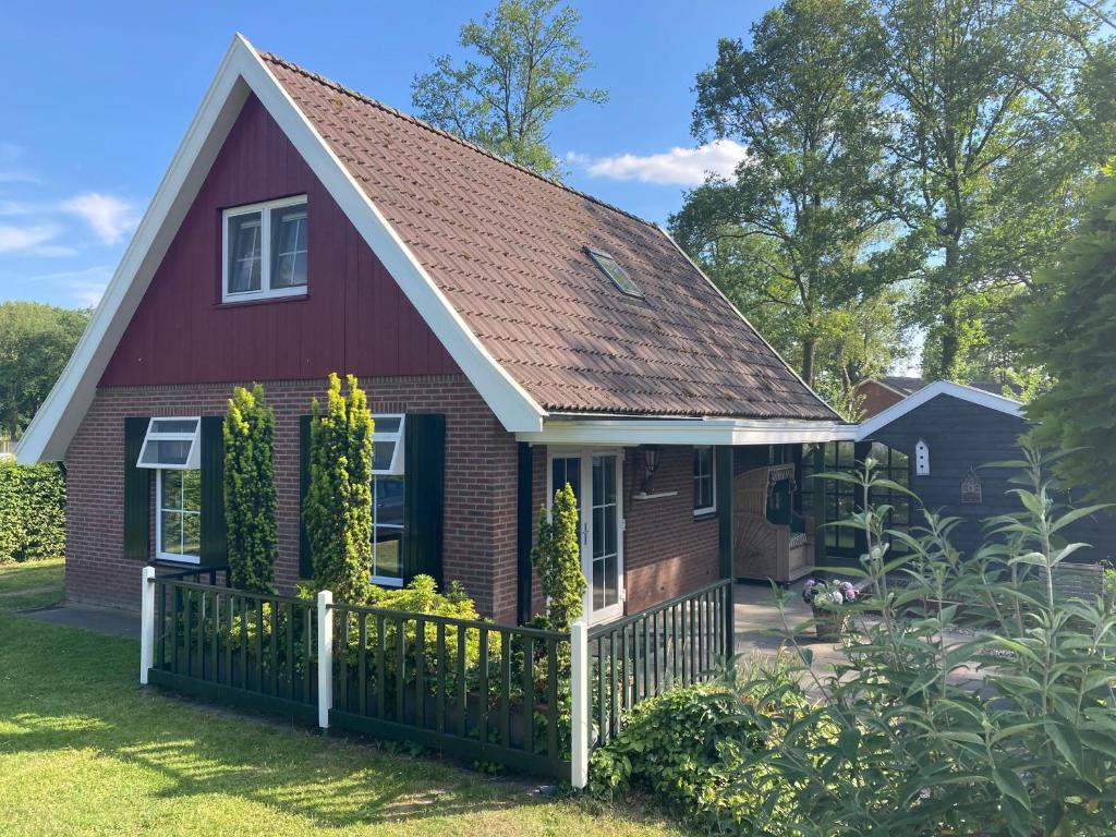 een rood huis met een wit hek bij Het Kottens Huisje in Kotten