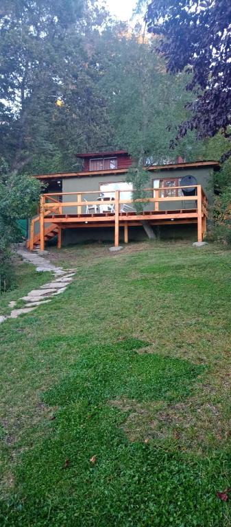 a house with a deck in the middle of a field at Cabaña Bariloche in San Carlos de Bariloche