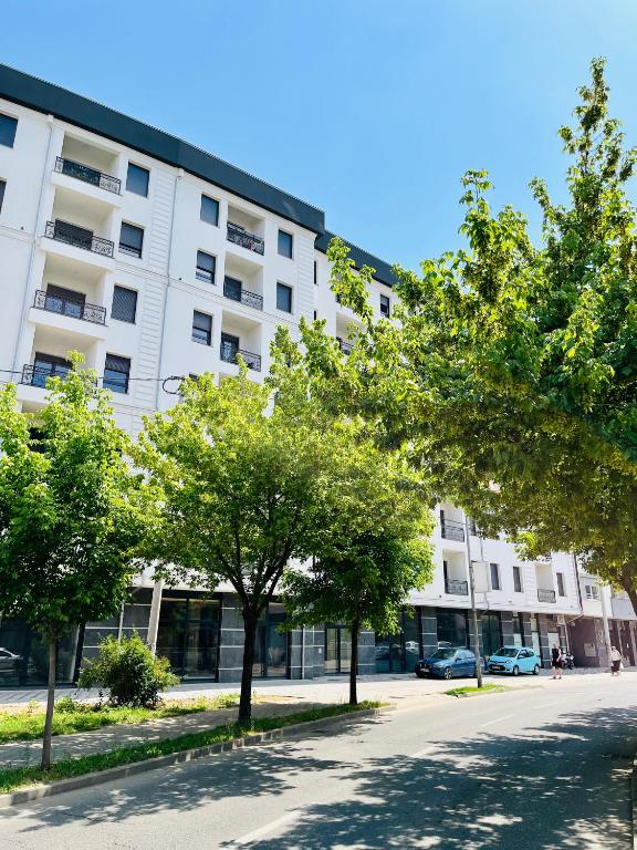 a white building with trees in front of it at Oasis Apartments in Bijeljina