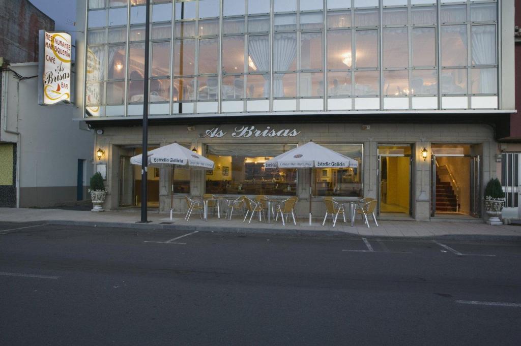 un restaurante con mesas y sillas frente a un edificio en Hotel As Brisas do Freixo, en O Freixo