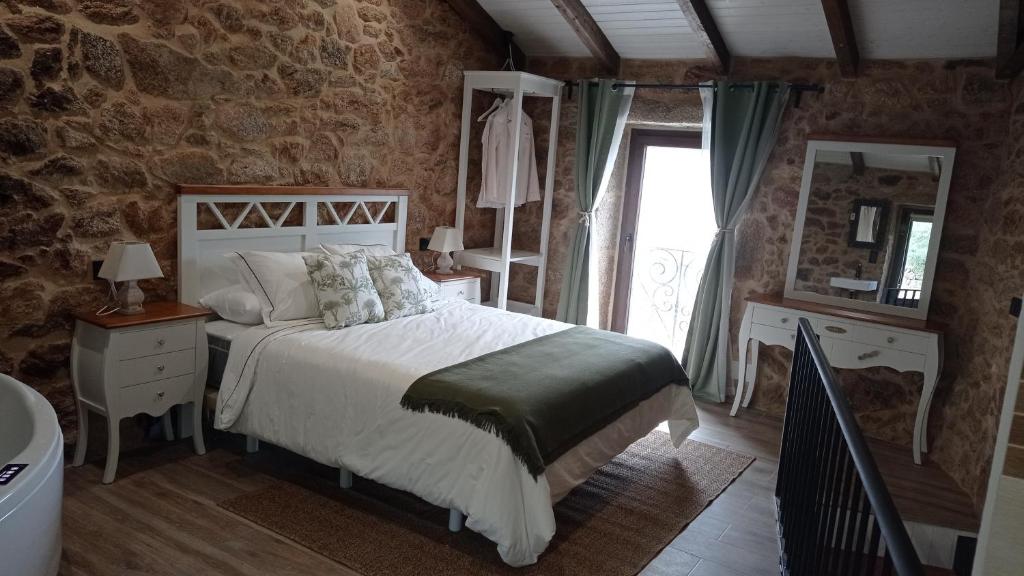 a bedroom with a bed and a mirror and a tub at A casiña do Pozo in Crucero