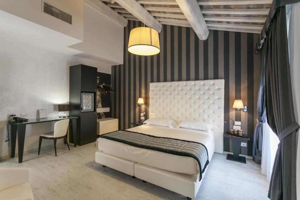 a bedroom with a white bed and a desk and a chair at Hotel Nazionale in Ferrara