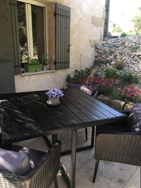 - une table en bois avec des chaises et des fleurs sur la terrasse dans l'établissement Juste derrière chez nous, à Boulbon