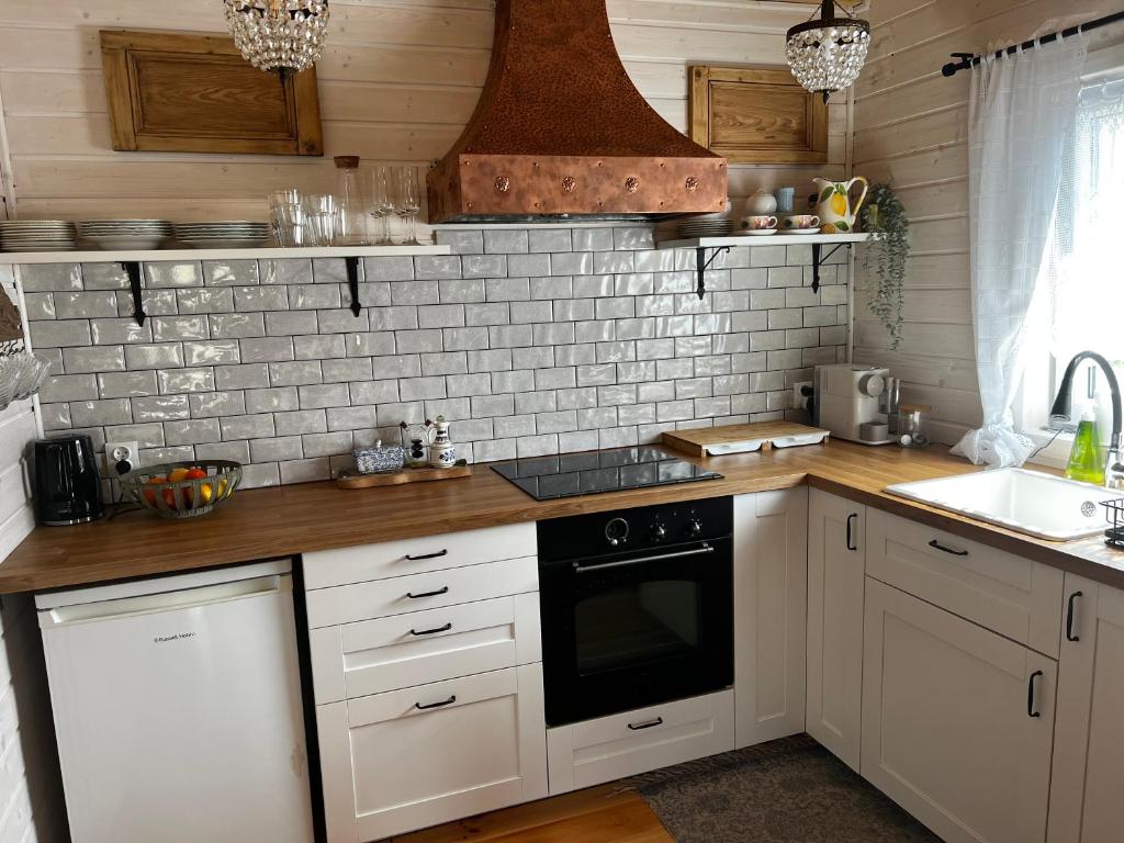 a kitchen with white cabinets and a stove top oven at Domek Anuszka in Sztutowo