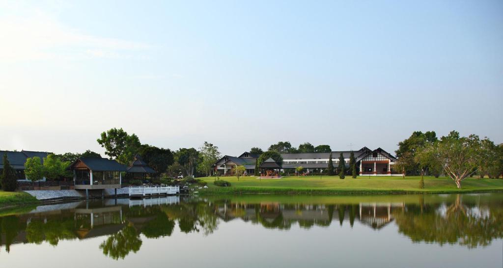 Blick auf einen See mit einem Gebäude im Hintergrund in der Unterkunft Korat Resort Hotel in Nakhon Ratchasima