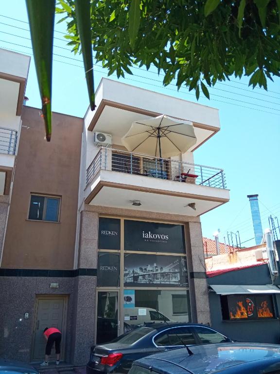 un edificio con balcone e ombrellone di Holiday's Nea Peramos Kavala's a Néa Péramos