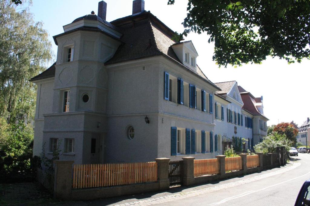 ein großes weißes Haus mit einem Zaun davor in der Unterkunft Apartments Villa del Arte in Nürnberg