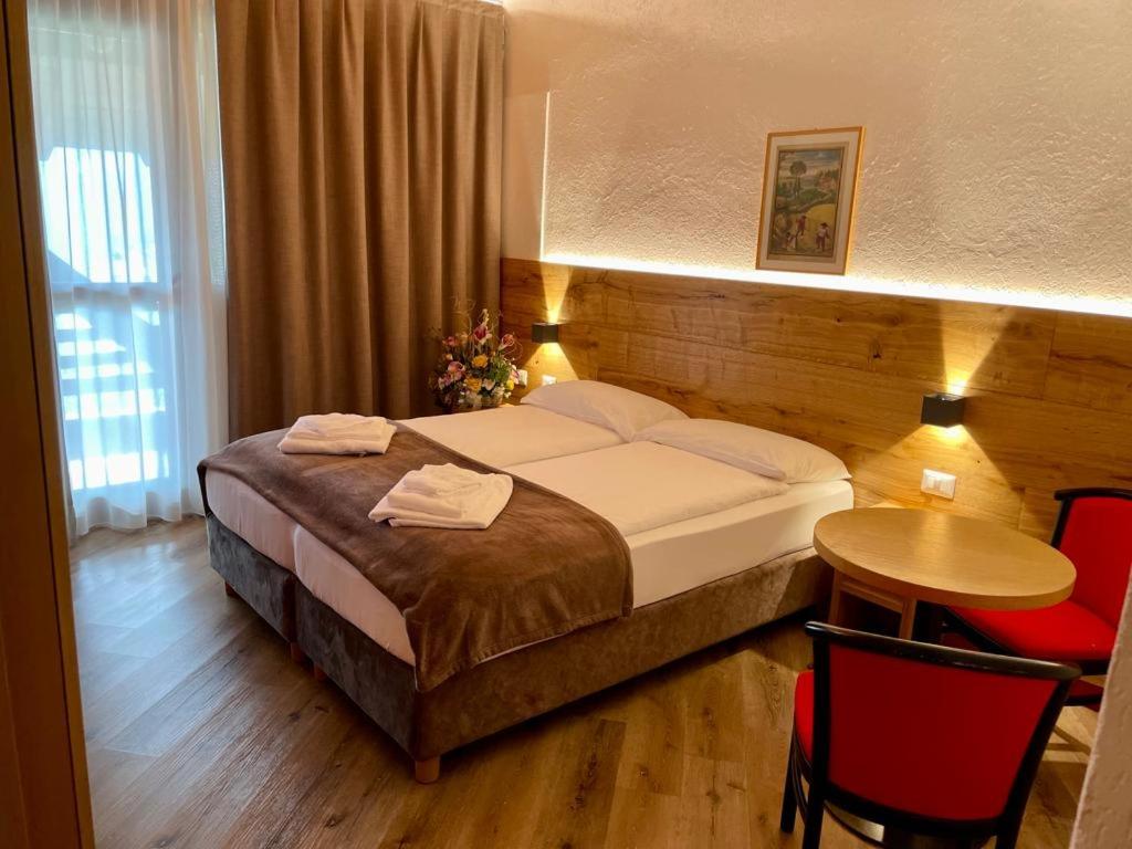 um quarto de hotel com uma cama, uma mesa e cadeiras em Dependance Soran-H. San Lorenzo em San Lorenzo in Banale