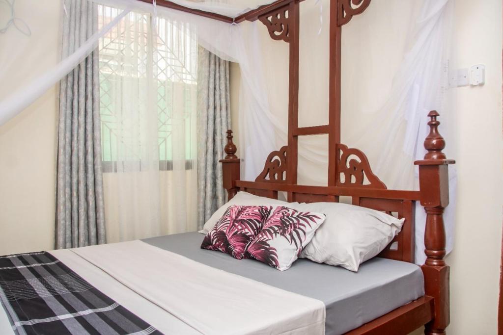 1 dormitorio con cama con dosel y almohada en Amarossi Elephant-One Bedroom Apartment,Mtwapa, en Mtwapa