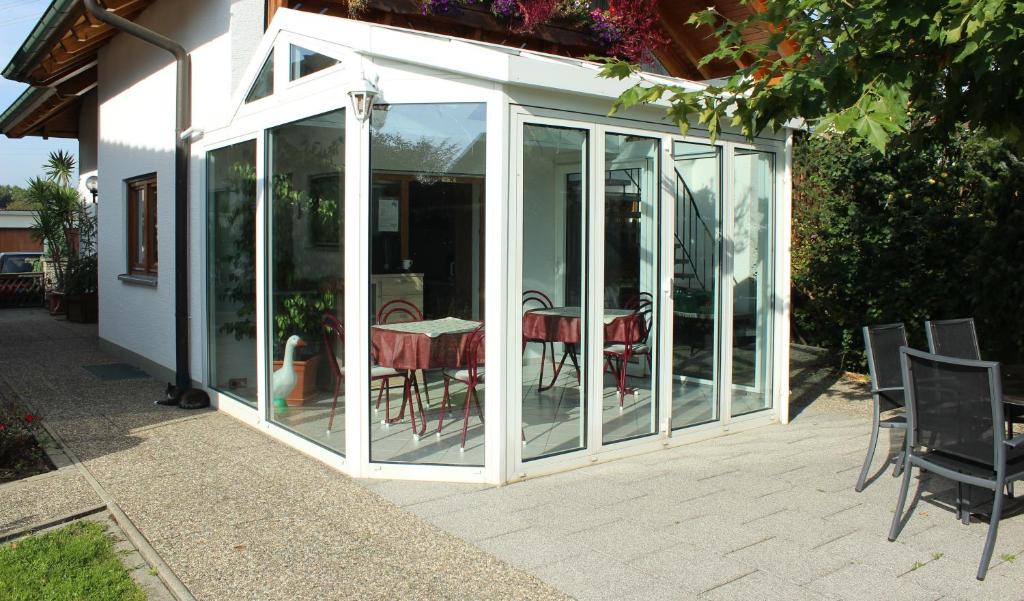 une véranda avec une table et des chaises sur une terrasse dans l'établissement Bodensee Unterkunft, à Bermatingen