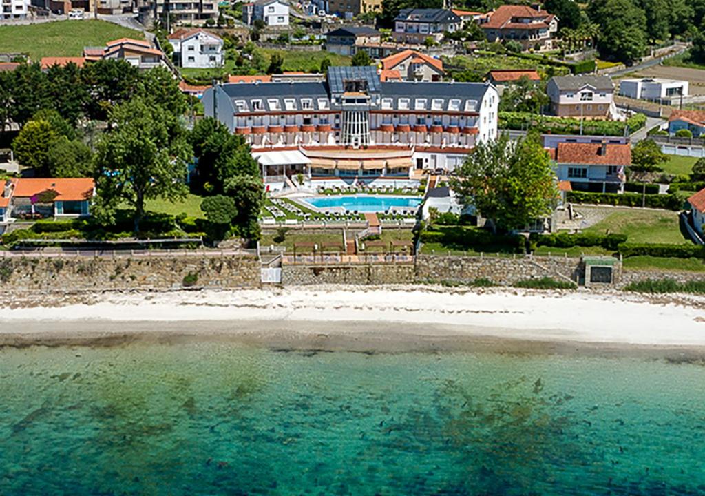 a beach scene with a large building at Hotel Spa Nanin Playa in Sanxenxo