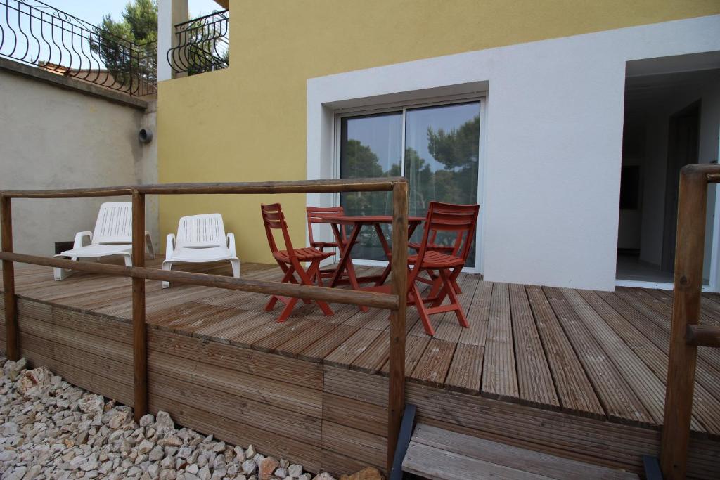 une terrasse en bois avec des chaises et une table dans l'établissement Chez Audrey dans la pinède, à Ensuès-la-Redonne