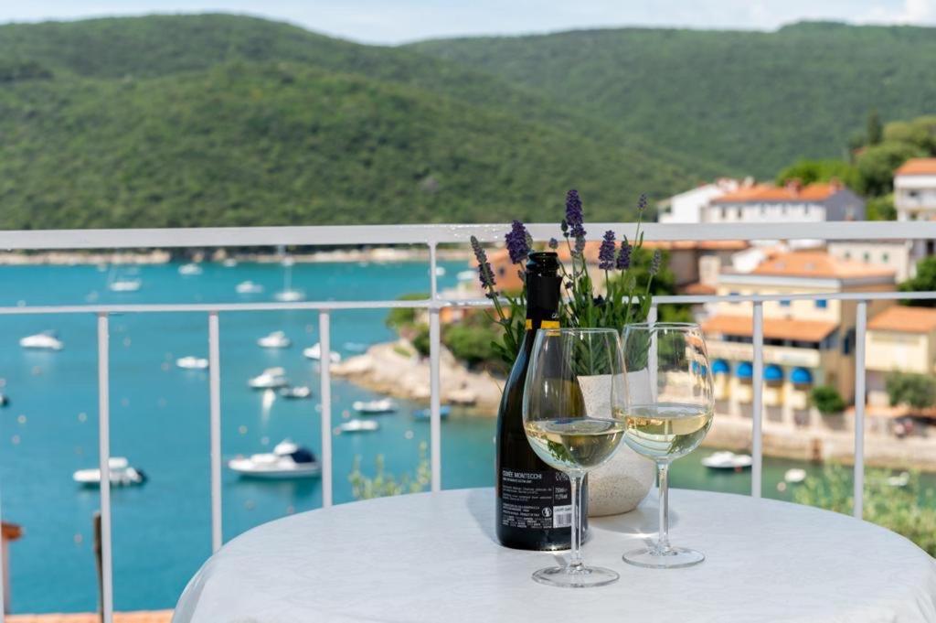 a bottle of wine sitting on a table with two glasses at Jadranka in Rabac