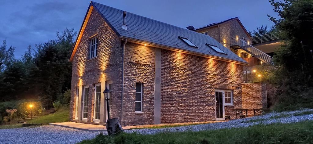 une maison en briques avec des lumières sur son côté dans l'établissement Domaine Le Haut-Vent, à Fosses-La-Ville