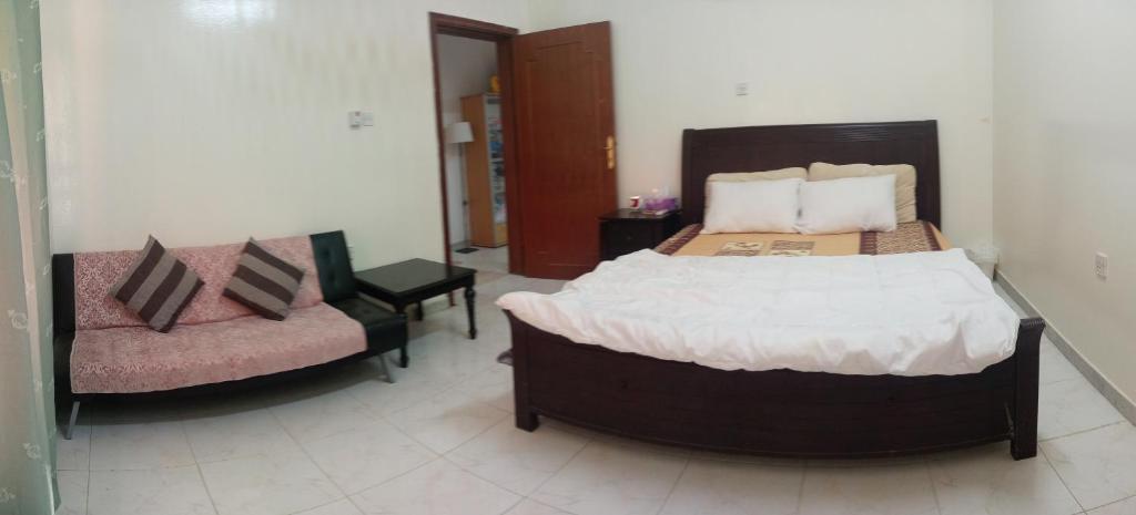 a bedroom with a large bed and a chair at Jaleen in Al 'Ayn