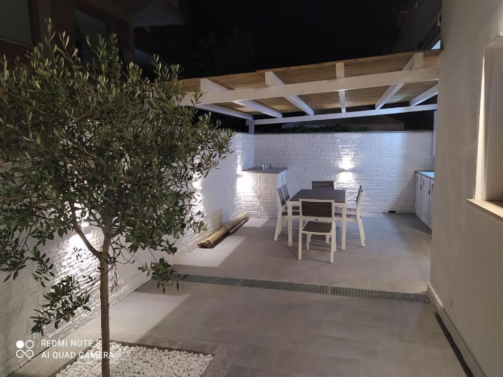 a patio with a table and chairs and a tree at Perla Vacanza in Santa Marinella