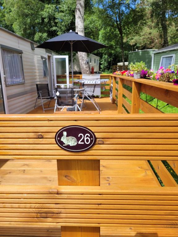 a wooden deck with a table and an umbrella at The Rabbit Hill Holiday Home in Ballantrae
