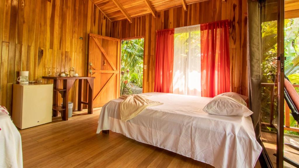 - une chambre avec un lit dans une pièce dotée d'une fenêtre dans l'établissement Arenal Rústic Lodge, à Fortuna