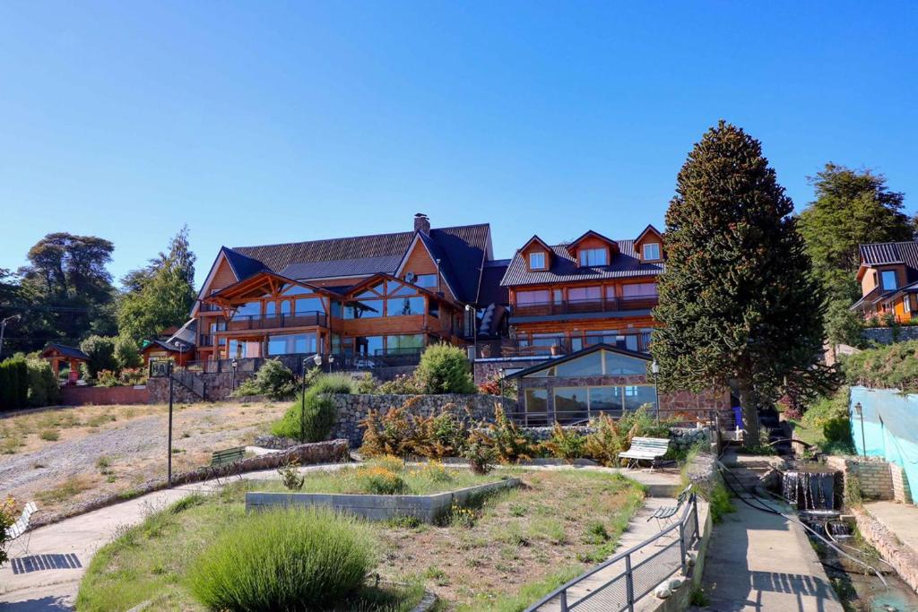 un gran edificio de madera con un jardín delante de él en Le Château en San Carlos de Bariloche