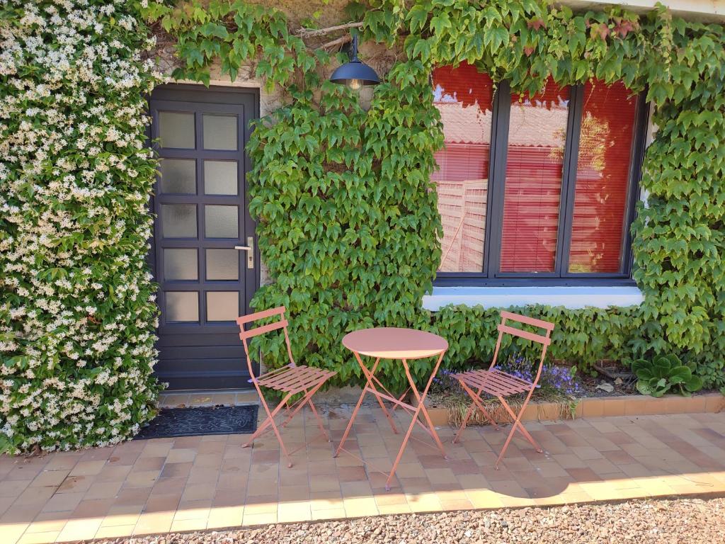 dos sillas y una mesa frente a una puerta en Les Studios de la longère by KARMA, en Andres