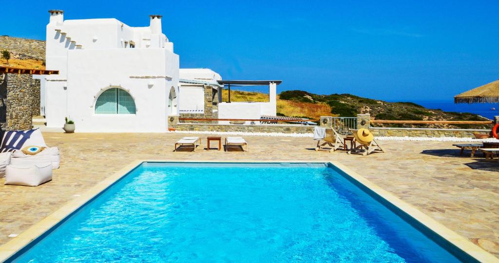 a blue swimming pool in front of a white house at Villa Mira Paros - Luxury Suites in Kampos Paros