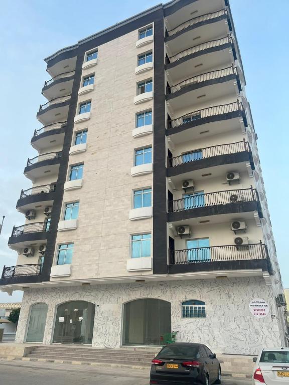 a tall building with balconies on the side of it at Aknan Center Market in Salalah