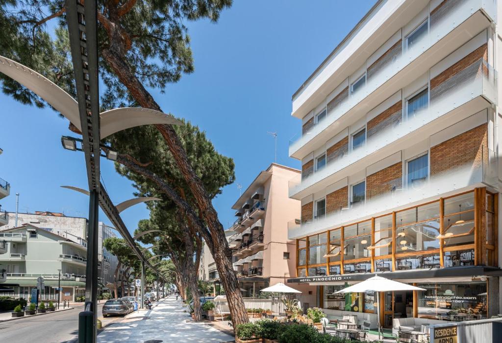 a street view of a building with tables and umbrellas at Hotel Pinocchio in Cattolica