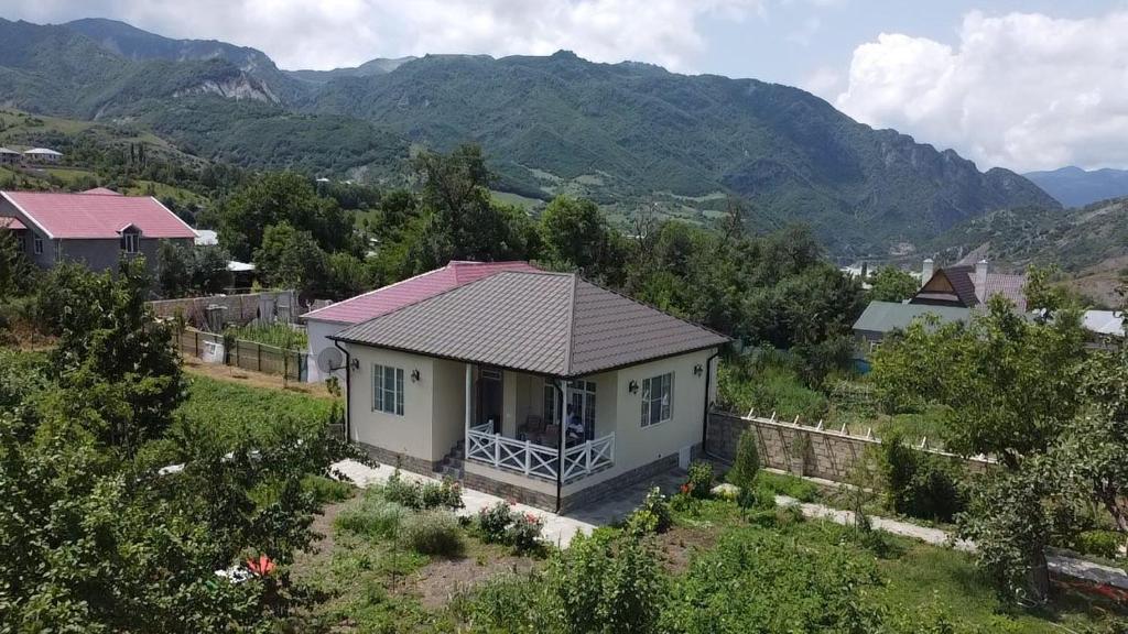 una pequeña casa en un campo con montañas en el fondo en Abbasov's guest house-In Lahij, en Lahıc