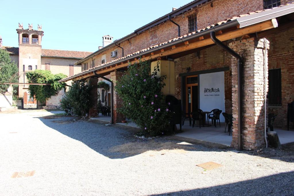 - un bâtiment en briques avec une table et des chaises à l'extérieur dans l'établissement Ostello Artemista Ass. Ostelli Lombardia, à Spessa