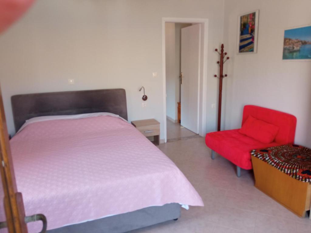 a bedroom with a bed and a red chair at Pedi Breeze in Symi
