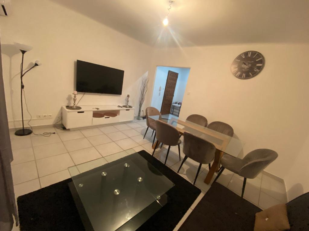 een woonkamer met een tafel en stoelen en een televisie bij Grand Appartement lumineux 75m2 in Avignon