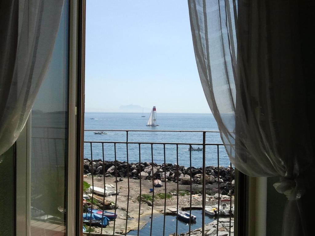 a window with a view of the ocean and a sailboat at B&B Borgo Marinaro in Pozzuoli