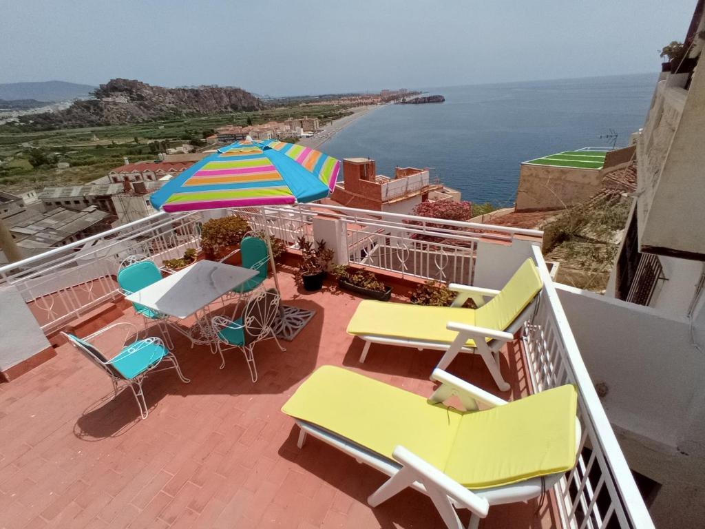 a balcony with chairs and a table and an umbrella at VILLA PANORAMA El Mediterráneo a tus pies. in Salobreña