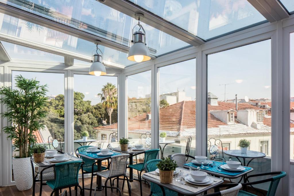 un salón acristalado con mesas, sillas y ventanas grandes en Marino Lisboa Boutique Guest House, en Lisboa