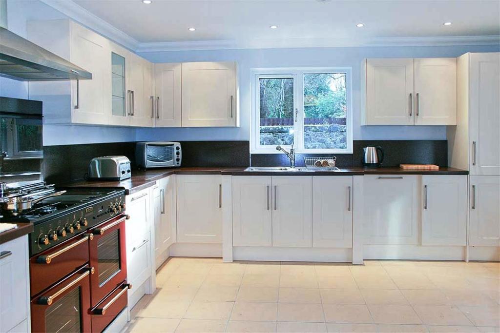 a kitchen with white cabinets and a stove top oven at Hillview House Hostel Inverness in Inverness