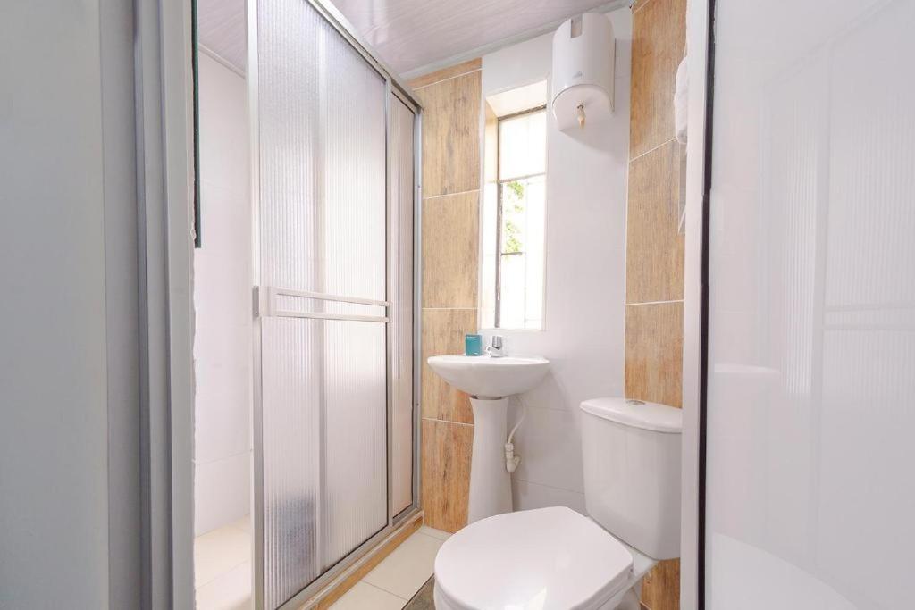 a white bathroom with a toilet and a shower at Hotel La Castellana in Manizales