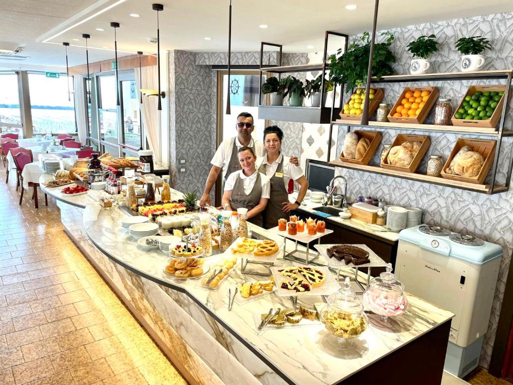 a group of three men standing behind a buffet table with food at Hotel Flamingo in Gatteo a Mare