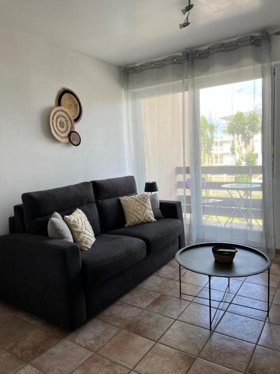 sala de estar con sofá negro y mesa en Le petit Cabourgeais, en Cabourg