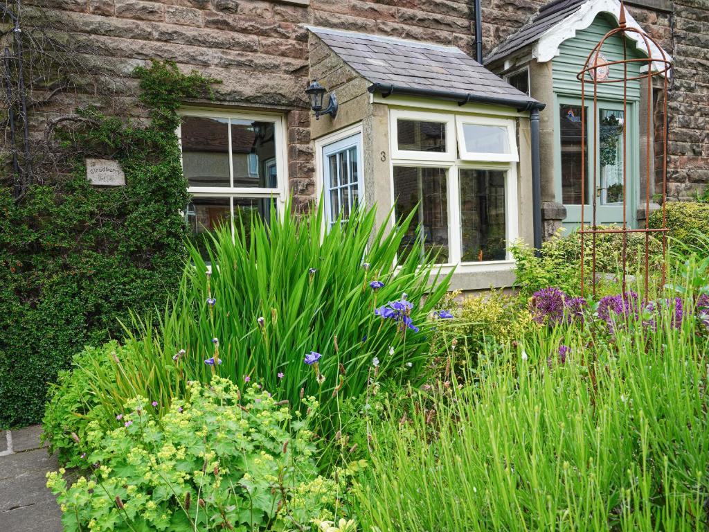 a garden with flowers in front of a house at Cloudberry Cottage in Stanton in Peak