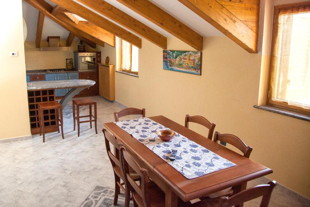 una cucina e una sala da pranzo con tavolo e sedie in legno di The Sweet Garret ad Agerola