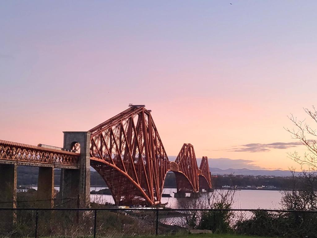 a bridge over a river with a person standing on it at Three Bridges Waterfront in North Queensferry