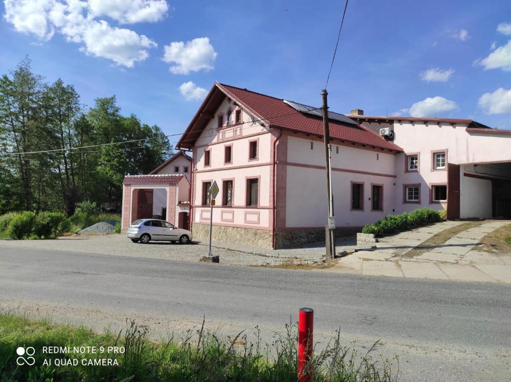 uma casa branca com um carro estacionado ao lado de uma rua em Příjemné ubytování na farmě 