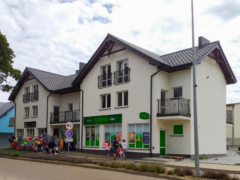 a white building with people standing outside of it at Willa Luna in Jarosławiec