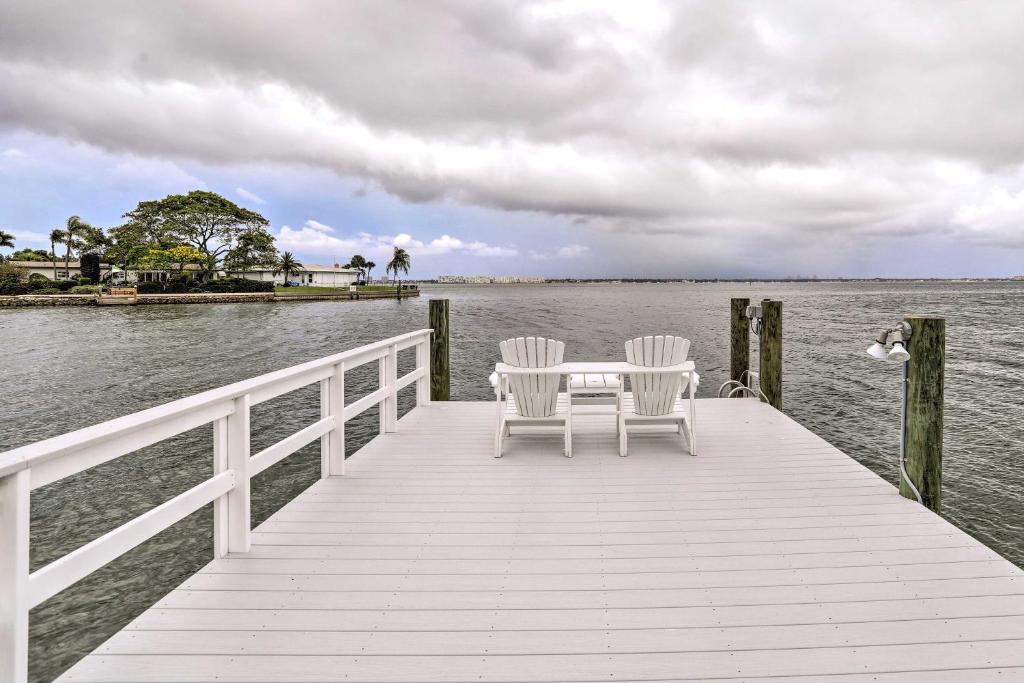 Un muelle de madera con dos sillas y una mesa sobre el agua. en Bayfront St Pete Beach Home with Outdoor Pool!, en St Pete Beach