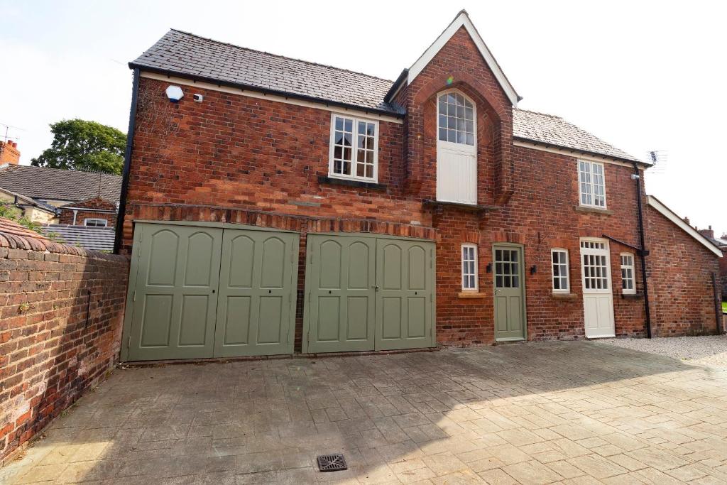 a brick building with green garage doors on it at The Olde Coach House in Chesterfield