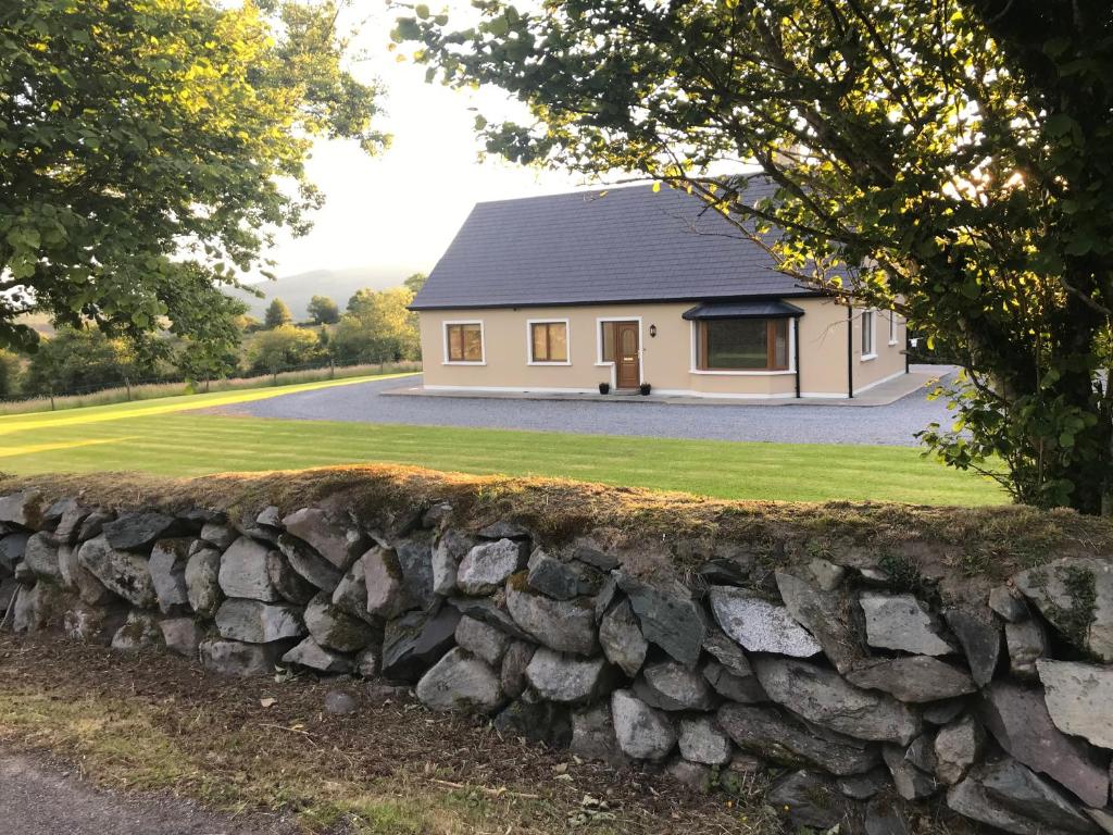 eine Steinmauer vor einem Haus in der Unterkunft Lissyclearig Lodge in Kenmare