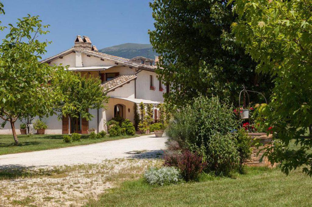 a large white house with trees and a driveway at Agriturismo Il Barco in Spello